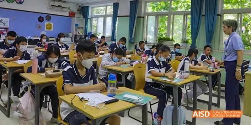 Students wearing masks working individually at desks in a classroom at Beijing 21st Century School.