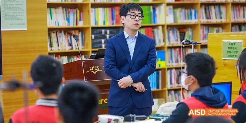 A teacher speaking to students in a library setting at Beijing 21st Century School.