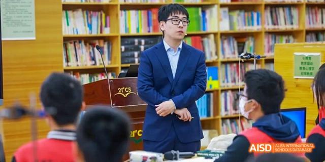 A teacher speaking to students in a library setting at Beijing 21st Century School.