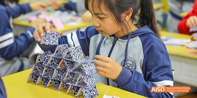 A student's hands are busy assembling a complex geometric model at Beijing 21st Century School.
