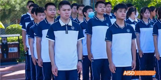 A group of male students in white and blue shirts standing together at Beijing 21st Century School.