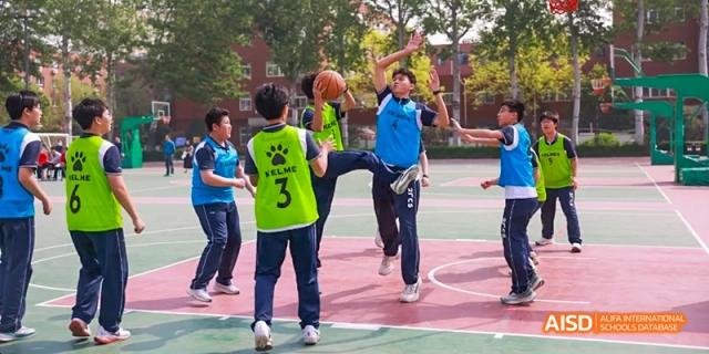 Students playing basketball on an outdoor court at Beijing 21st Century School.