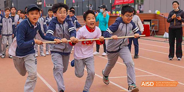 A team of students energetically participating in a tug-of-war competition at Beijing 21st Century School.