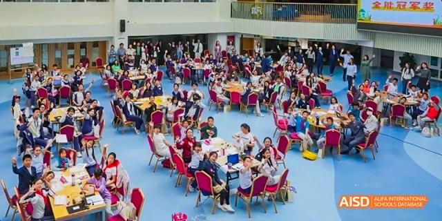 A large group of students seated on the floor for an indoor event at Beijing 21st Century School.