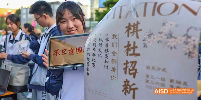 A student standing next to a large poster at Beijing 21st Century School.