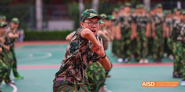 A male student performing a hip-hop dance outdoors at Beijing 21st Century School.