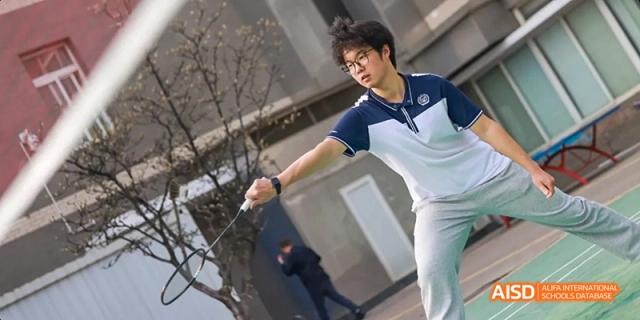 A student in a white uniform performing a dynamic jump kick at Beijing 21st Century School.