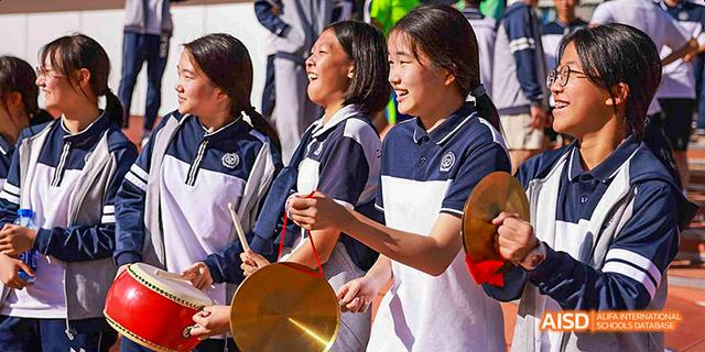 Female students in uniforms singing together on a stage at Beijing 21st Century School.