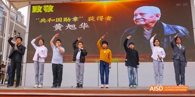 A group of people bowing on a stage at Beijing 21st Century School.