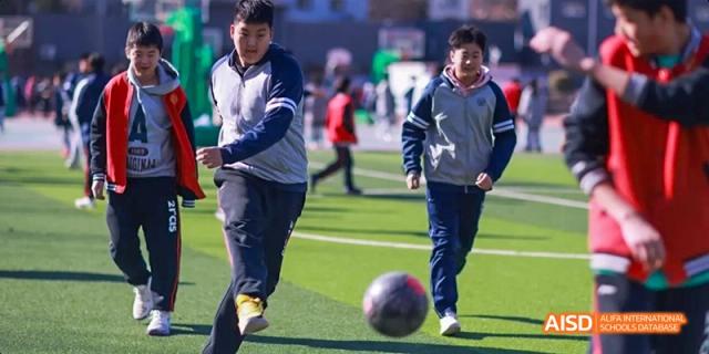 Students playing soccer on a field at Beijing 21st Century School.