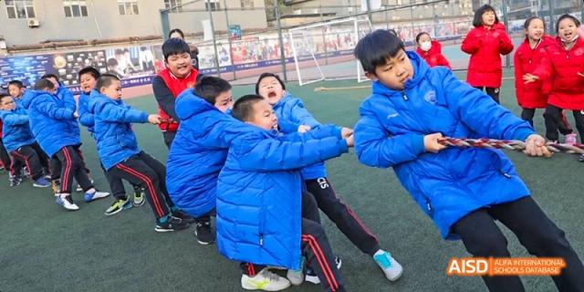 Students playing a game of tag on a field at Beijing 21st Century School.