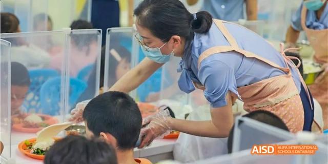 A teacher helping a student get food during lunchtime at Beijing 21st Century School.