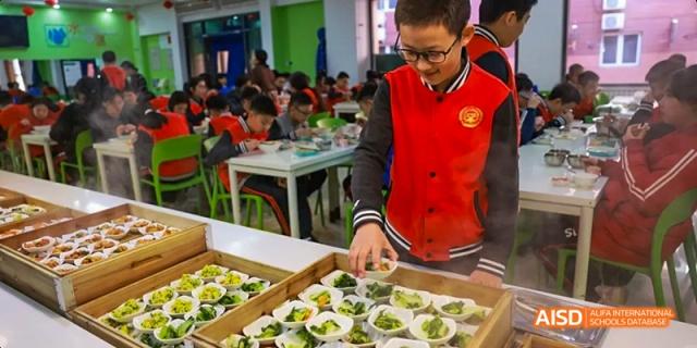 Students and a teacher working together to prepare food at Beijing 21st Century School.