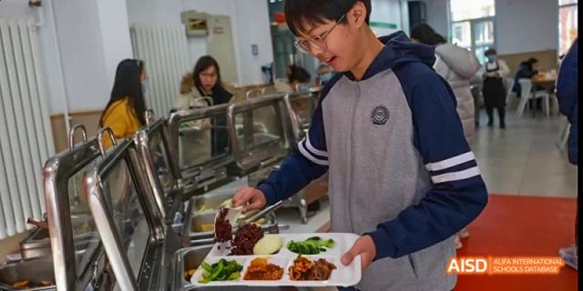 A student selecting food from a serving line in the school cafeteria at Beijing 21st Century School.