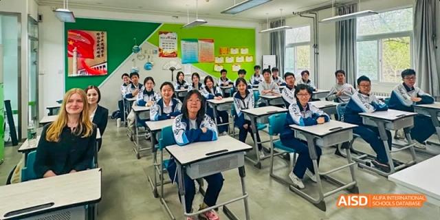 A teacher and students are seated at a long table, engaged in a discussion at Beijing 101 Middle School.