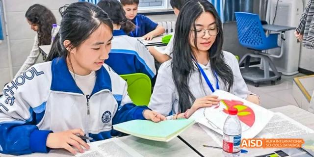 Two female students are working on a project with a book at Beijing 101 Middle School.