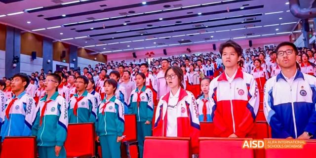A group of students in red and white uniforms are sitting in a classroom at Beijing 101 Middle School.