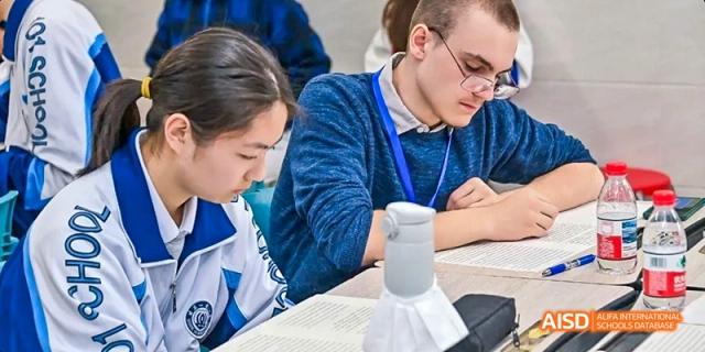 A female student is looking at a laptop while a teacher or a mentor is standing beside her at Beijing 101 Middle School.