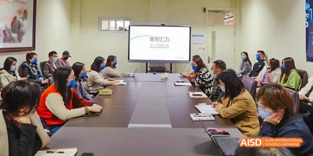 A group of students are seated in a conference room with a large screen displaying a presentation at Beijing 101 Middle School.