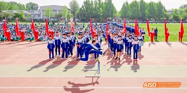 A large group of students in blue uniforms are performing in a parade with props at Beijing 101 Middle School.