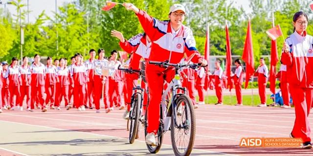 Students in red and white uniforms are riding bicycles in a synchronized formation at Beijing 101 Middle School.