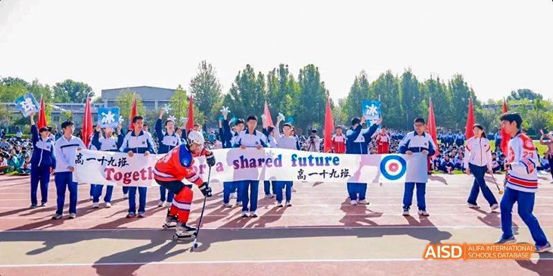 A group of students in red and white uniforms are holding a banner that says "Shared Future" in both Chinese and English at Beijing 101 Middle School.
