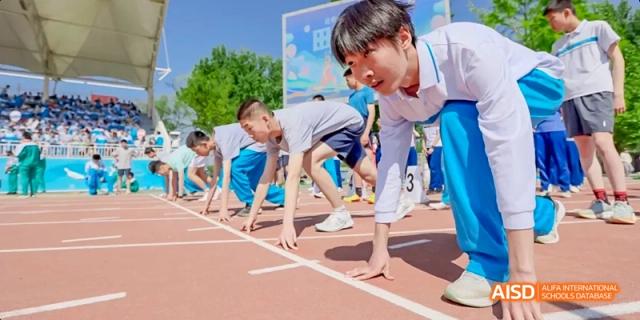 A male student in a blue shirt is in a starting position, ready to run a race, at Beijing 101 Middle School.