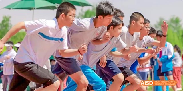 Three male students are running a race on a sports track at Beijing 101 Middle School.