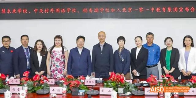 A group of adults, including teachers and officials, are seated at a table during an event at Beijing 101 Middle School.