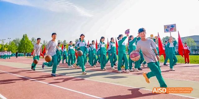 A large group of students in green and white uniforms are marching in a parade on a sports track at Beijing 101 Middle School.