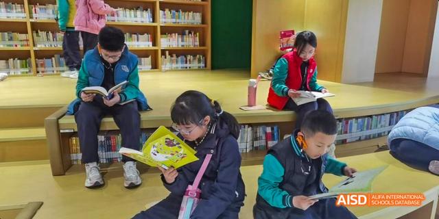 Beijing Bacui Bilingual School Young students reading books in the school library.