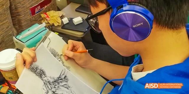 Beijing Bacui Bilingual School A student wearing headphones draws in a sketchbook.