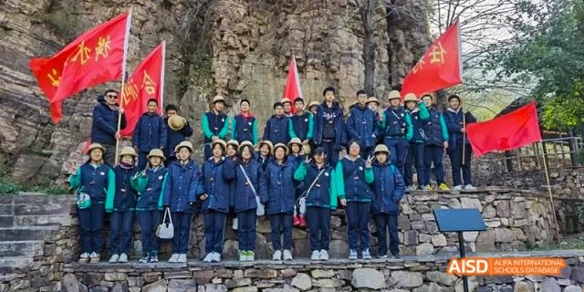 Beijing Bacui Bilingual School A large group of students poses for a photo outdoors in front of a rocky cliff.