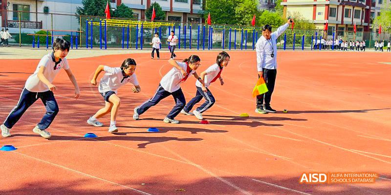Beijing Bacui Bilingual School A group of students crouches at the starting line of a race on a running track.