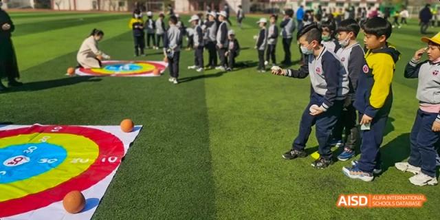 Beijing Bacui Bilingual School A student wearing a mask on a green field participating in a sports activity.