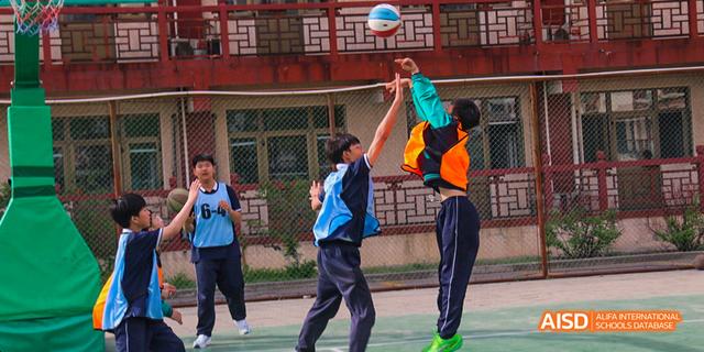 Beijing Bacui Bilingual School Two female students play basketball, with one attempting to block a shot.