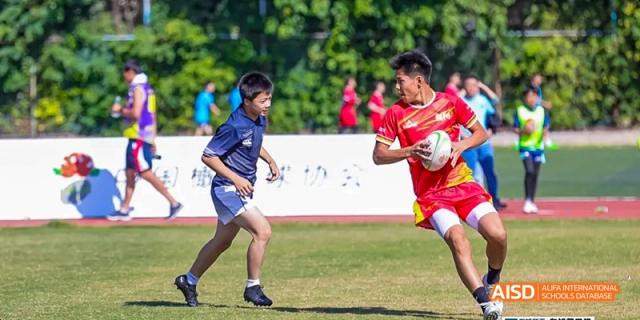 Beijing Bacui Bilingual School Two male students are running and competing during a sports match on a grassy field.