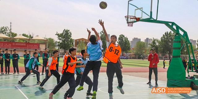Beijing Bacui Bilingual School A group of students playing a game of basketball on an outdoor court.