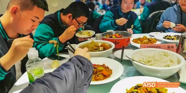 Beijing Bacui Bilingual School A group of students eat a meal together, using chopsticks and bowls.