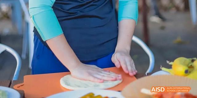 A photo showing a person kneading dough with their hands, at Beijing Enlighten School.