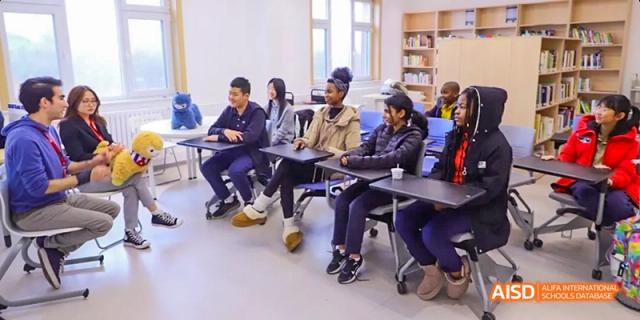 A photo showing a group of students with a teacher in a classroom, at Beijing Enlighten School.