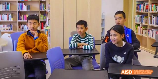 A photo showing students sitting at a table and studying, at Beijing Enlighten School.