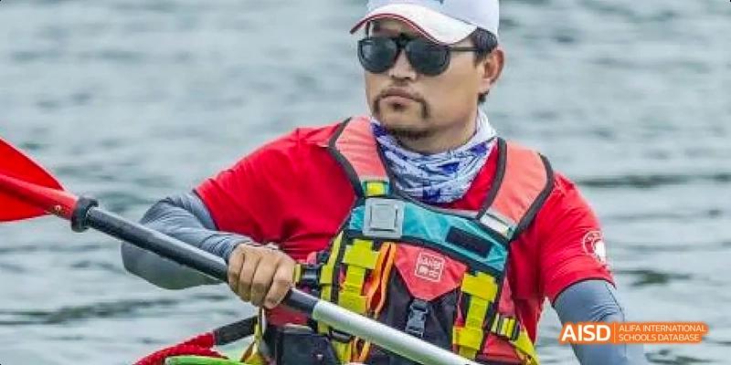 A photo showing a person in a red life jacket holding a paddle in a boat, at Beijing Enlighten School.