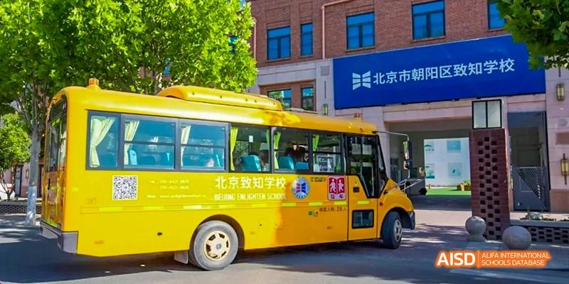 A photo showing a yellow school bus parked in a school, at Beijing Enlighten School.