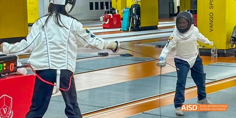 A photo showing two students with a teacher in a fencing competition, at Beijing Enlighten School.