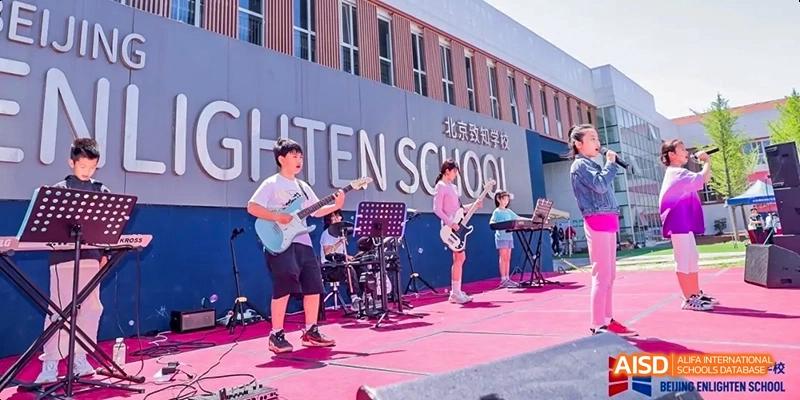 A photo showing students performing on a stage. They are performing a musical show, at Beijing Enlighten School.