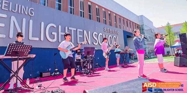 A photo showing students performing on a stage. They are performing a musical show, at Beijing Enlighten School.