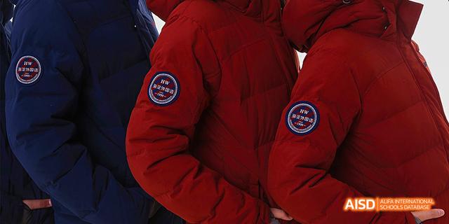 A close-up of a student's uniform sleeve with the school emblem of Beijing Haidian Foreign Language Academy.
