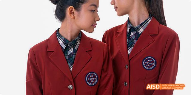 Two female students from Beijing Haidian Foreign Language Academy smiling in their red school jackets.