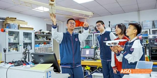 A student from Beijing Haidian Foreign Language Academy holding a model drone in a science or robotics lab.